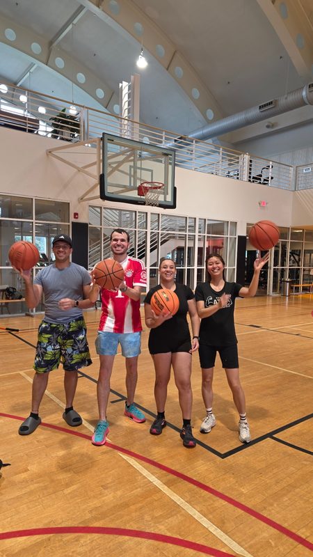 Four friends holding basketballs on an indoor court