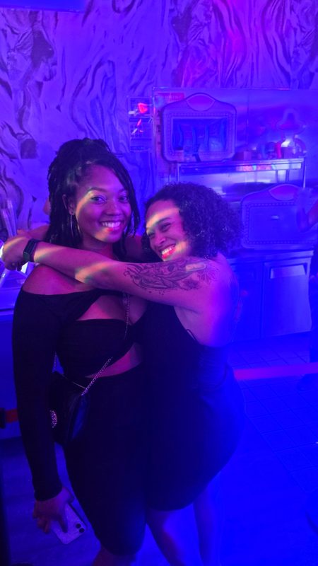 Two friends embracing in a bar lit in deep blue