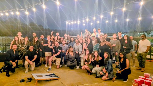 A large group photo on a patio under string lights
