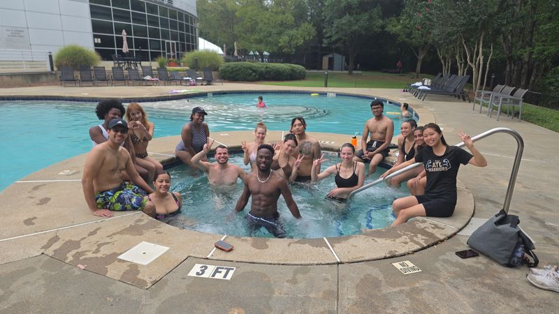 Friends gathered in a hot tub beside a pool on a summer day