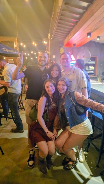 A group posing together at a bar under string lights
