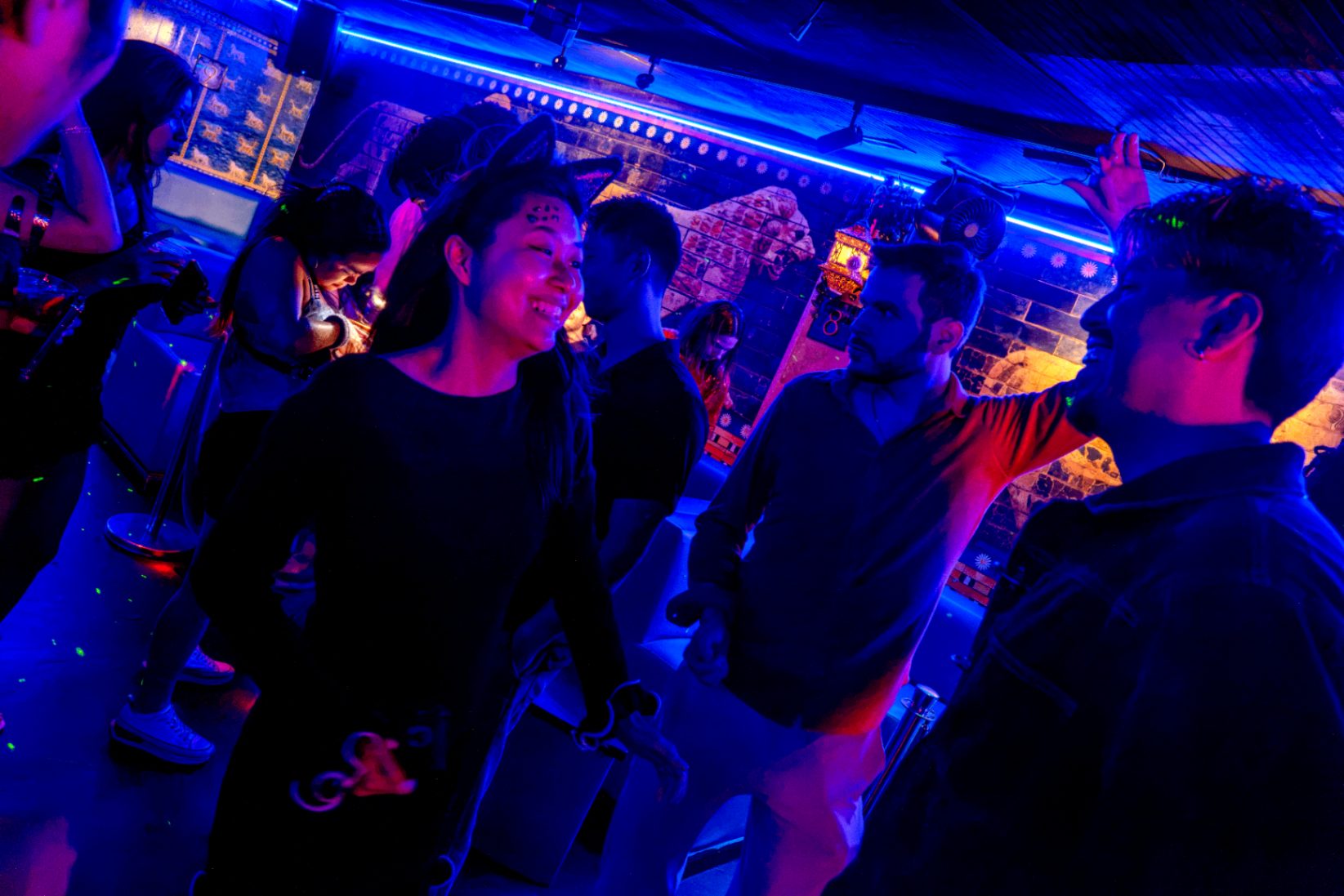 Members dancing and talking in a blue-lit lounge