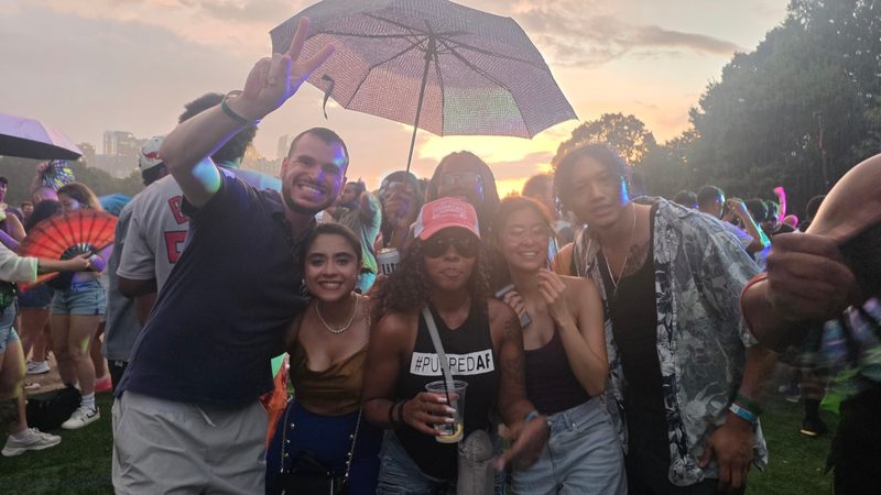 A group of friends gathered outdoors at a festival at sunset