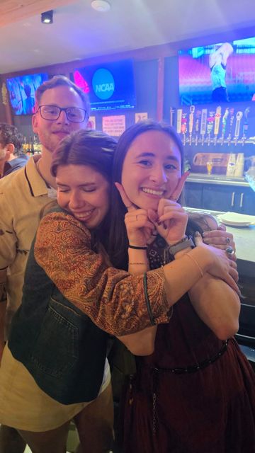 Friends hugging and laughing at a sports bar