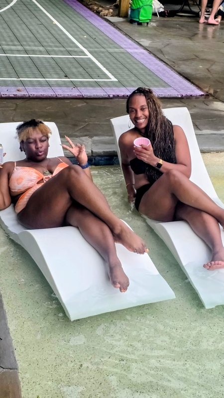 Two friends relaxing on loungers in the pool