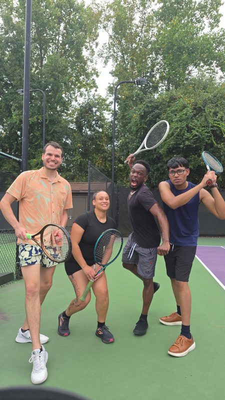 Four friends with tennis rackets on an outdoor court