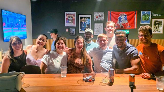 A group lined up at a bar table smiling for the camera